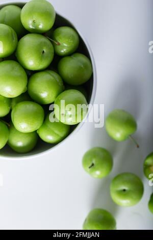 Prugne verdi fresche in una ciotola bianca. Vista dall'alto. Foto Stock