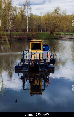 La barca di pulizia del fiume raccoglie i rifiuti sulla superficie dell'acqua del fiume. Cestino skimmer barca. Sistemi di rimozione dei detriti flottanti. Utilizzato per rimuovere i detriti flottanti Foto Stock