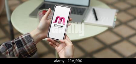 Vista ravvicinata della freelance femminile che si rilassa con il mock-up smartphone mentre si lavora in cortile Foto Stock