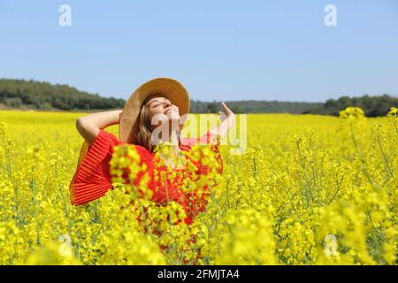 Donna eccitata in rosso che allarga le braccia in un giallo campo fiorito Foto Stock