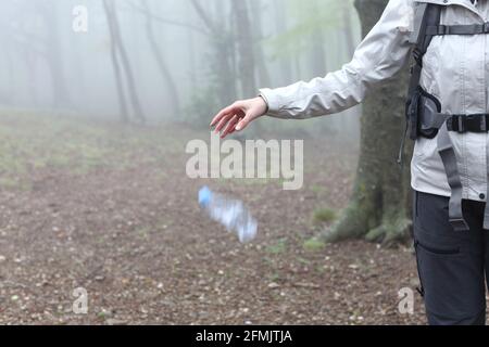 Primo piano di un trekker incCivil gettando spazzatura al terra in natura Foto Stock