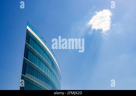 Moderno edificio per uffici con il sole che splende su di esso attraverso una nuvola. Foto Stock