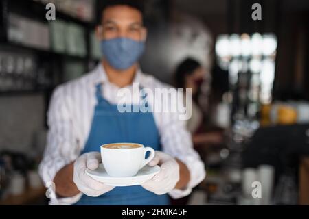 Ritratto del cameriere che serve caffè in caffetteria, piccola impresa, coronavirus e nuovo concetto normale. Foto Stock