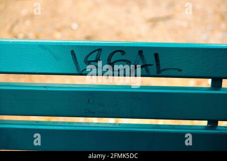 Closeup di una panchina del parco con una scritta 'LEGALE' su di esso; arte di strada e anti-razzismo Foto Stock