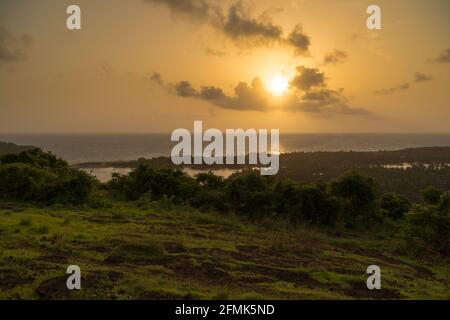 Tramonto che si abbassa sull'orizzonte. Splendida vista sul paesaggio e sull'oceano in lontananza. Colori vibranti e soffici e luce magica. Foto Stock