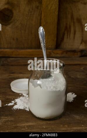 lievito in polvere in un vaso di vetro con un fondo di legno, o bicarbonato di sodio in un vaso, ingrediente per torte e molti altri usi Foto Stock