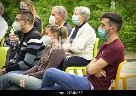 Il pubblico che indossa maschere covide al primo gioco in un parco all'aperto per la riapertura post-pandemica. Milano, Italia - Maggio 2021 Foto Stock