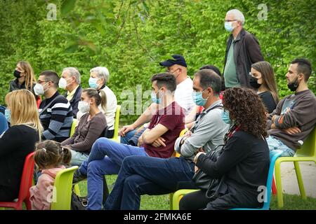 Il pubblico che indossa maschere covide al primo gioco in un parco all'aperto per la riapertura post-pandemica. Milano, Italia - Maggio 2021 Foto Stock