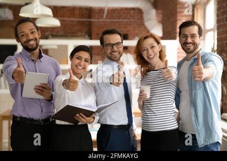 Gruppo di dipendenti sorridenti che mostra i pollici verso l'alto, guardando la fotocamera Foto Stock