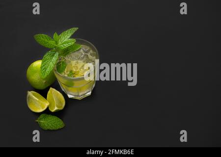 Vista dall'alto del cocktail mojito con lime verdi fresche e menta su sfondo scuro con spazio per la copia di testo o pubblicità. Foto Stock