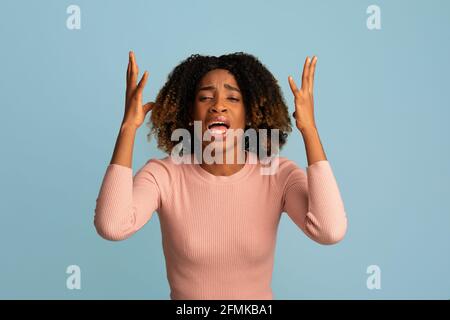 Perché me. Desperate Black Woman lamentarsi di qualcosa su sfondo blu, infelice sottolineato emotivo African American Female lutto, depresso Foto Stock