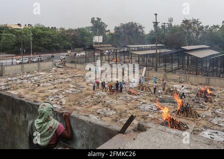 Delhi, India. 09 maggio 2021. Una donna guarda i parenti delle vittime del coronavirus (Covid-19) che eseguono gli ultimi riti durante una cremazione ad un crematorio a Nuova Delhi. L'India riporta 3, 66,161 nuovi casi, 3,754 decessi nelle ultime 24 ore. (Foto di Amarjeet Kumar Singh/SOPA Imag/Sipa USA) Credit: Sipa USA/Alamy Live News Foto Stock