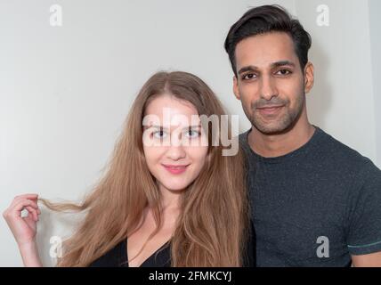 Allegra coppia interracial in posa sullo sfondo grigio chiaro Foto Stock