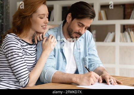 Primo piano felice coppia sposata millenaria firma contratto, accordo di chiusura Foto Stock