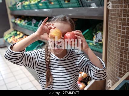 La bambina felice sceglie le mele in un negozio di alimentari. Shopping di alimentari divertente. Foto Stock