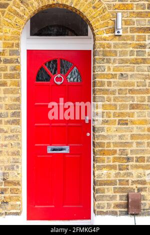 Porta d'ingresso in legno rosso in un edificio storico in mattoni Inghilterra Foto Stock
