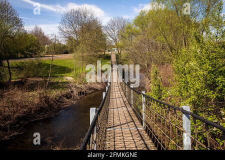 Ponte sospeso sul fiume Dhuenn nel Parco Neuland, Leverkusen, Nord Reno-Westfalia, Germania. Haengebruecke ueber die Dhuenn im Neuland-P. Foto Stock