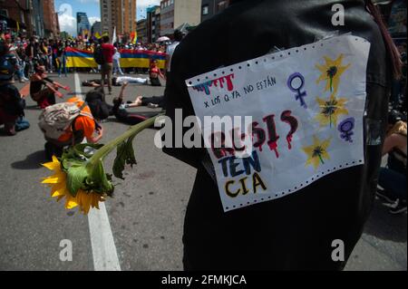 Un dimostratore porta un girasole e un segno che recita "per quelli che non sono più qui, resistenza" a Bogotà, Colombia, il 9 maggio 2021, come peac Foto Stock