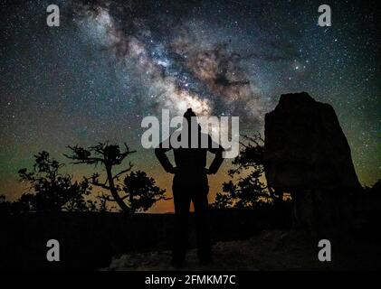 La Via Lattea che sorge sul Grand Canyon, con una persona in primo piano. Fotografato a Shoshone Point. Foto Stock