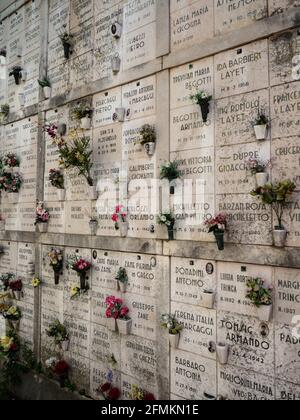 Vista closeup della tomba bianca in pietra decorata con fiori Al Cimitero di San Michele Venezia Veneto Italia Europa Foto Stock