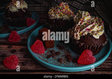 Delizioso cupcake di muffin al cioccolato con coloratissimi spruzzi di topin bianco crema, tartufi e caramelle a forma di cuore per la festa di San Valentino per l'amore Foto Stock