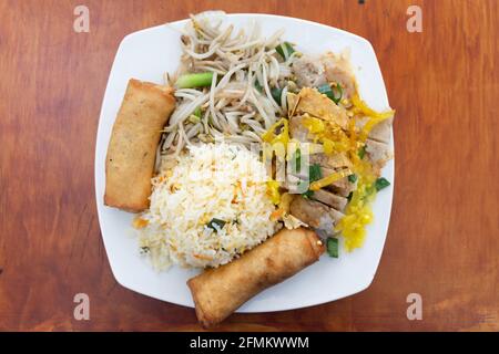 Vista dall'alto del riso fritto con involtini primaverili, pezzi di carne, peperoni piccanti e germogli di soia. Piatto tradizionale cinese dall'alto Foto Stock
