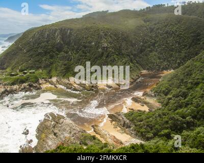 Vista sul fiume Loitterings, dove si diramano nell'oceano, tra le ripide foreste coperte montagne Tsitsikamma, Sudafrica Foto Stock