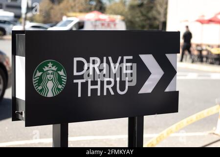 Courtenay, Canada - Aprile 22,2021: Le auto si allineano per ordinare il cibo usando la facilita' drive-thru al locale Starbucks Coffee Shop Foto Stock