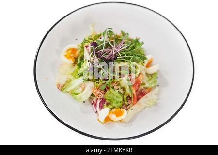 Vista dall'alto di un'insalata di verdure con verdure, uova e pomodori su sfondo bianco. Concetto di nutrizione adeguata per perdita di peso a casa. Foto Stock