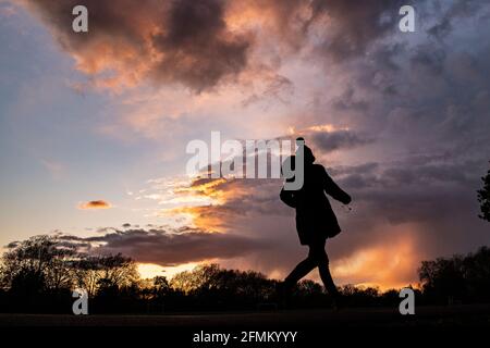 Una ragazza cammina a casa al tramonto indossando un cappello da bob Foto Stock