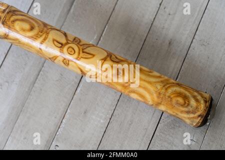 Didgeridoo strumento musicale closeup su sfondo grigio tavole. Tromba australiana tradizionale fatta di legno e decorata con disegno astratto Foto Stock