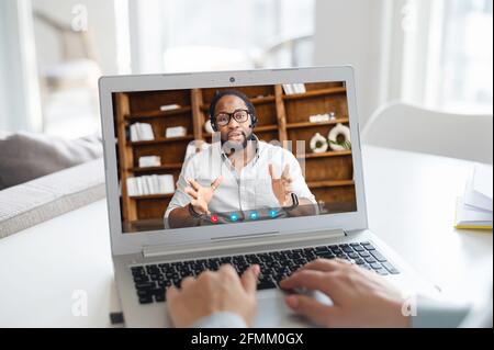 Sicuro afroamericano maschile tutor online, business coach sullo schermo del computer è in corso di formazione online, femminile utilizzando il laptop per la connessione video, conferenza virtuale con il collega Foto Stock
