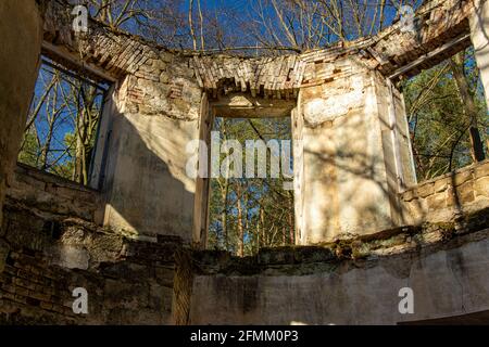 Vista attraverso i fori per porte e finestre in un rovina abbandonata nei boschi Foto Stock