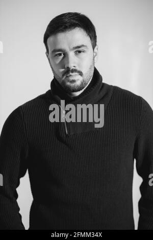 Scala di grigi di un giovane maschio caucasico con un serio faccia che indossa una camicia a collo di turtleneck Foto Stock