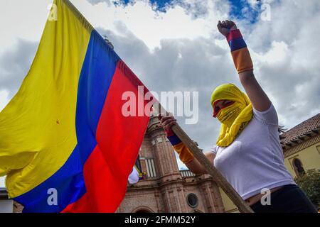 Passo, Narino, Colombia. 9 maggio 2021. Il demostratore Hooded alza il pugno e le onde della bandiera colombiana nel canto della lotta e supor per lo sciopero nazionale a passo Narino il 9 maggio 2021 Photo by: Camilo Erasso/Long Visual Press Credit: Camilo Erasso/LongVisual/ZUMA Wire/Alamy Live News Foto Stock