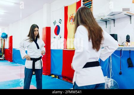 Abiti giovane donna nel suo vestito taekwondo davanti speculare Foto Stock