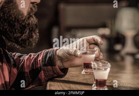 Bearded uomo shot cocktail. Tiri di tequila, vodka, whisky, rum. Barman in pub. Colpo di tequila. Cocktail colorati al bar Foto Stock