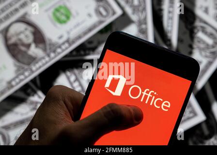 In questa illustrazione fotografica il logo del software americano della multinazionale tecnologica Microsoft, Office, visualizzato su uno smartphone con la valuta USD (dollaro USA) sullo sfondo. Foto Stock