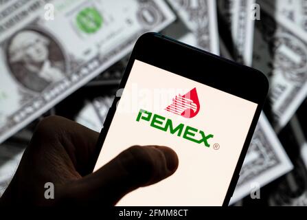 In questa illustrazione la compagnia messicana del petrolio e del gas Petróleos Mexicanos, meglio conosciuta come Pemex, logo visto su uno smartphone con la valuta USD (dollaro USA) in background. Foto Stock