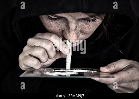 Droga Addict sniffing e russare cocaina, velocità, eroina o altra droga con soldi arrotolati su specchio con sfondo scuro, dipendenza, droghe, depresso Foto Stock