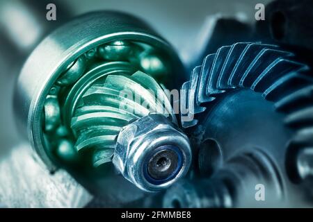 Dettaglio artistico delle ruote dentate in acciaio all'interno della smerigliatrice angolare in tonalità verde blu. Meccanismo del motore dell'attrezzo di potenza con dado di bloccaggio o cuscinetto a sfere. Foto Stock