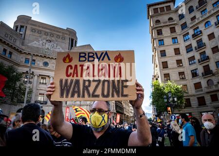 Barcellona, Spagna. 10 maggio 2021. Un manifestante detiene un cartello che dichiara la Catalogna come zona di guerra durante la manifestazione di fronte alla sede della banca a Vía Laietana.convocata dai sindacati bancari, Centinaia di lavoratori bancari del Banco Bilbao Vizcaya Argentaria (BBVA) si sono riuniti davanti alla sede centrale di Vía Laietana per protestare contro il documento di regolamento sull'occupazione (ERE) che l'entità intende presentare domanda con il licenziamento di più di 3,000 lavoratori. (Foto di Paco Freire/SOPA Images/Sipa USA) Credit: Sipa USA/Alamy Live News Foto Stock