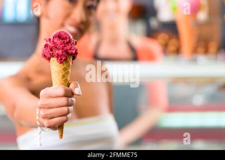 Giovani clienti di sesso femminile in una gelateria con gelato cornet Foto Stock
