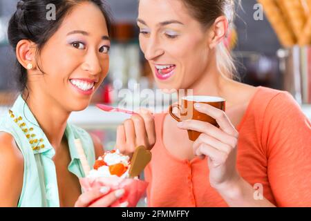 Giovani clienti di sesso femminile o con gli amici in una gelateria con gelato cornet Foto Stock