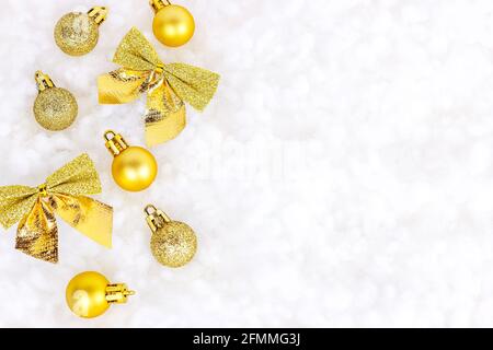 Decorazioni natalizie in oro brillante (nastri, baubles, ornamenti) piatte posate su bianco fondo di neve artificiale con spazio di copia. Natale e Capodanno tradizionale Foto Stock