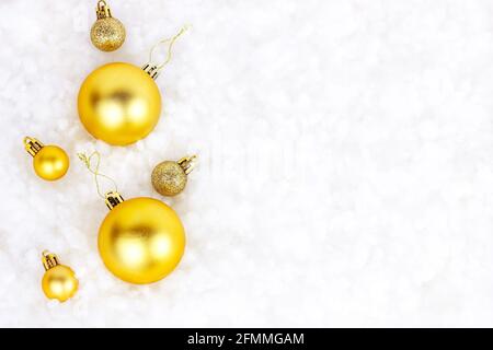 Decorazioni natalizie in oro brillante (nastri, baubles, ornamenti) piatte posate su bianco fondo di neve artificiale con spazio di copia. Natale e Capodanno tradizionale Foto Stock