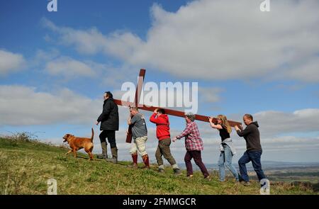 Portando una croce di legno fino Cam Peak il Venerdì Santo prima della Domenica di Pasqua in una passeggiata di testimone, Gloucestershire Foto Stock