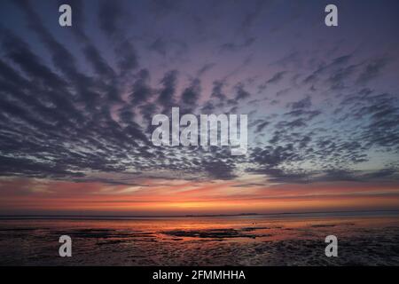 Pellworm, Germania. 10 maggio 2021. Il sole tramonta sul Mare del Nord al largo dell'isola di Pellworm. Credit: Marco Brandt/dpa/Alamy Live News Foto Stock