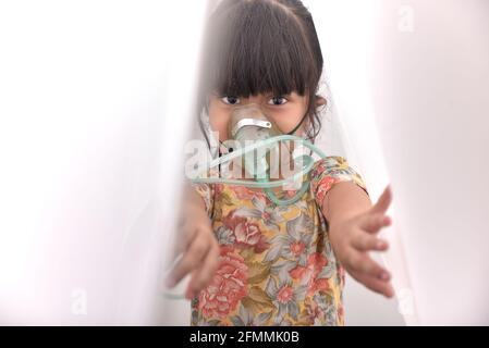 Bambina in una maschera nebulizzatrice, trattamenti per la pandemia virale a casa quarantena Foto Stock