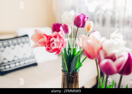 Interni e arredamento domestico. Tulipani freschi in fiore disposti in vasi in accogliente soggiorno. Fiori freschi e colorati Foto Stock